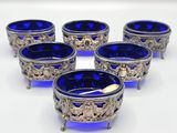 six blue glass bowls with silver decorations on them on a white surface
