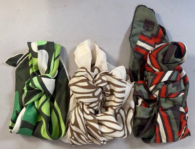four different colored scarves are lined up on a white surface