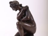 an image of a bronze statue of a woman sitting on a wooden base