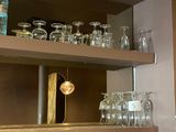 bottles and glasses are on a shelf in a kitchen
