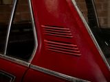 a red car parked in a garage next to a brick wall