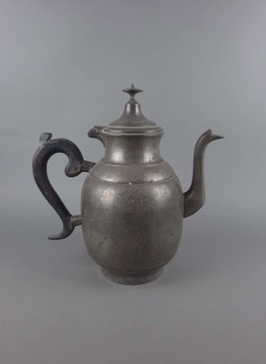 une vieille théière en argent surmontée d'un oiseau