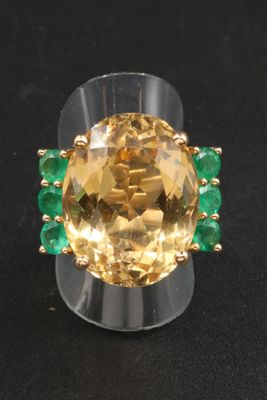 an image of a ring with a yellow topazr surrounded by emeralds
