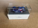 a blue toy car in a clear box on the floor