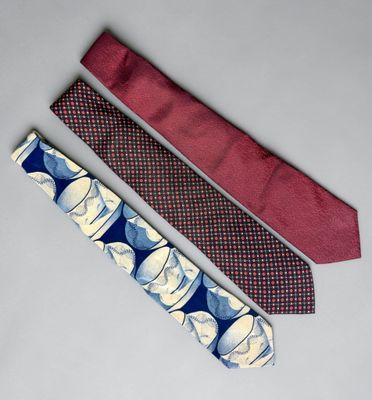 three ties with different designs on them sitting on a white surface