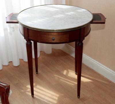 une petite table avec un plateau en marbre sur un plancher en bois
