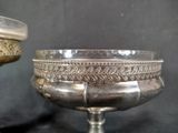 a silver bowl sitting on a table next to a silver cup