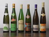 Des bouteilles de vin sont alignées sur une table devant un mur blanc.