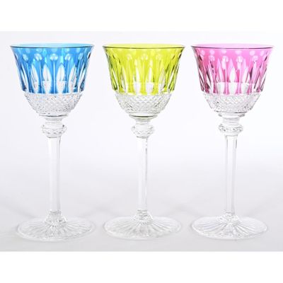 three different colored wine glasses sitting next to each other on a white surface