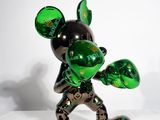 une statue de Mickey Mouse verte et noire posée sur une surface blanche