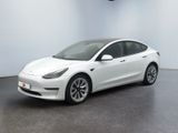 une Tesla Model 3 blanche garée dans une pièce blanche