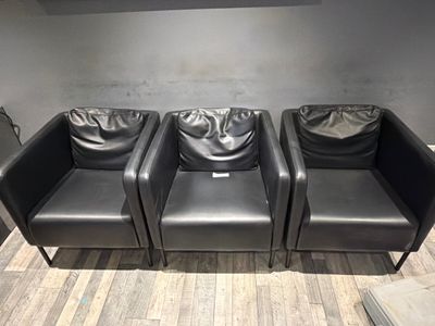 three black leather chairs sitting in a row on the floor