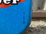 a close up of a blue beer bottle on the ground