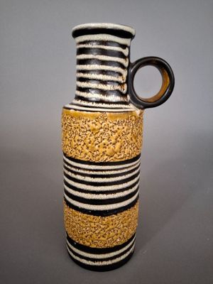 a black and white striped vase with a brown handle