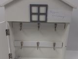 a small white house with key hooks on the door