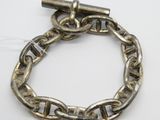une image représentant un bracelet en argent muni d'un fermoir, posé sur une surface blanche