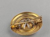 a close up of a gold plated brooch with a compass on it
