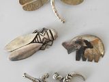 three silver brooches, a dragonfly, a tiger, and a dragonfly