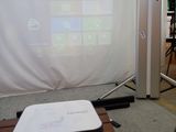 un projecteur posé sur une table devant un écran de projection