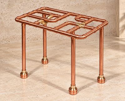 une photo d'une table fabriquée à partir de tuyaux en cuivre posée sur un sol en marbre