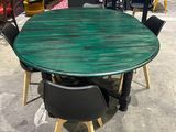 green round dining table with four black chairs and a red chair