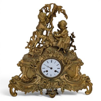 a gold clock with figures on it on a white background