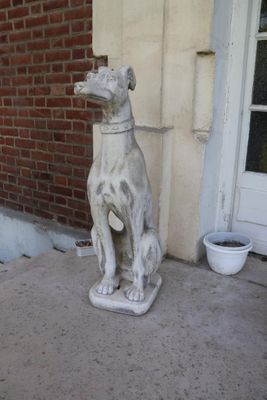 une statue représentant un chien assis sur le trottoir