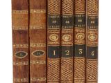 cinq vieux livres sont alignés sur une surface blanche