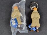 a keychain with a figure of a man in a trench coat and a bag of money