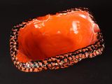 an orange and black bowl sitting on top of a black surface