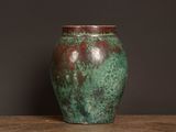 a green vase sitting on a table with a black background