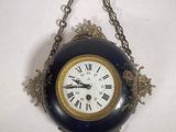 a clock hanging from a chain on the wall
