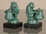 two statues of monkeys sitting on top of a glass table