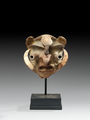 a close up of a sculpture of a face on a stand