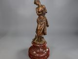 une statue antique en bronze représentant une femme tenant un enfant dans ses bras, posée sur un socle
