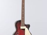 an old red guitar hanging from a string on a white wall