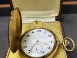 une montre de poche en or dans un écrin posé sur une table