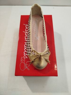 des ballerines dorées ornées d'un nœud, posées sur une boîte rouge