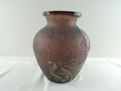 un vase marron orné de motifs dorés, posé sur une table blanche