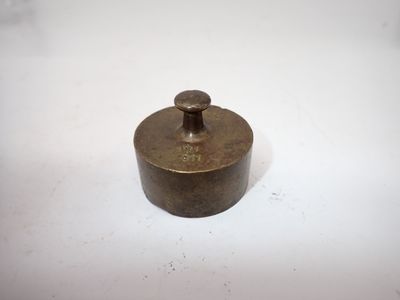 une vieille casserole en laiton avec un couvercle, posée sur une surface blanche