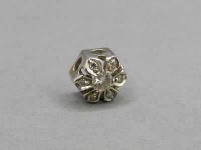 a close up of a silver bead with a flower design on it