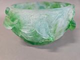 a glass bowl with green leaves on it on a table