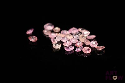 some pink diamonds on a black surface with a black background