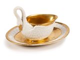 a white swan on a gold saucer on a plate