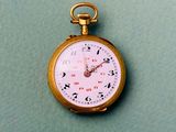 une montre de poche en or posée sur une surface verte