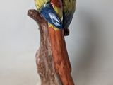 a figurine of a parrot perched on a tree branch