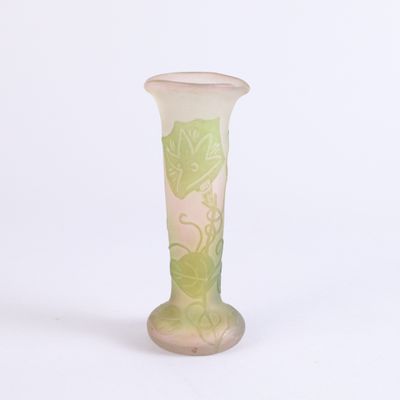 un vase en verre orné de feuilles vertes, posé sur une surface blanche