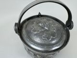 a silver pot with a handle on a white surface