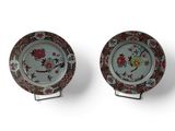 two plates with floral designs on them sitting on a stand