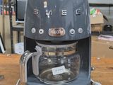 a coffee maker sitting on a wooden table in a room